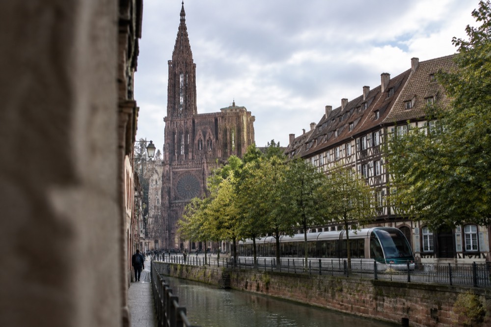 A modern Strasbourg tram passing along a tree-lined avenue