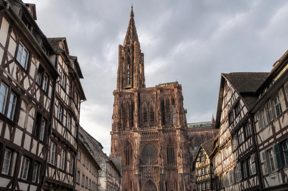 Cobbled square with a cathedral facade rising above the roofs of old houses
