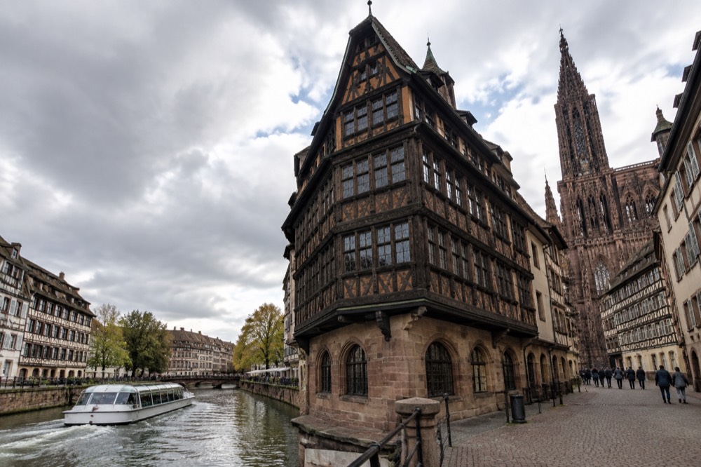 Passenger boat moving along a river channel past old timbered buildings