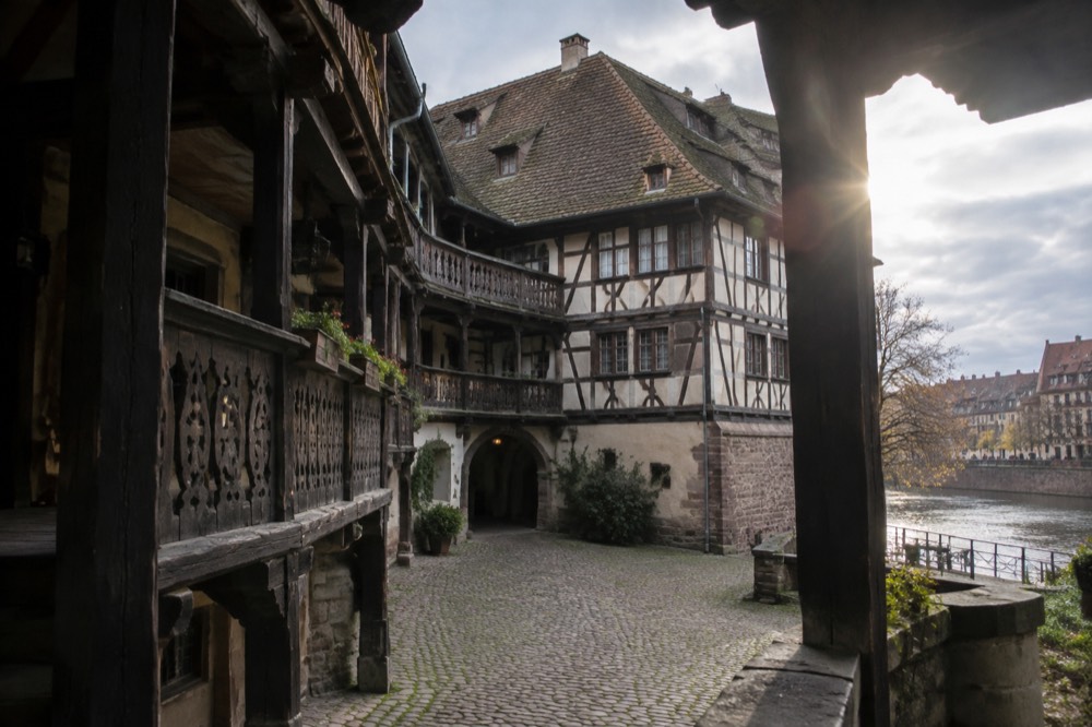 Timber-framed facade with carved wooden galleries above a cobbled lane