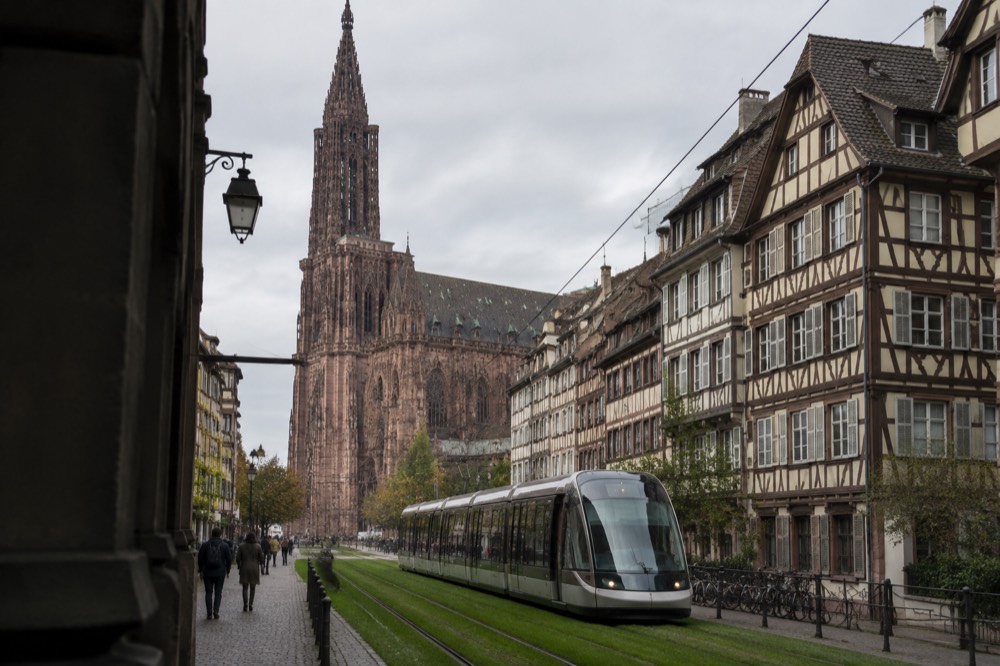 Tram gliding along a grassed track past historic Strasbourg facades