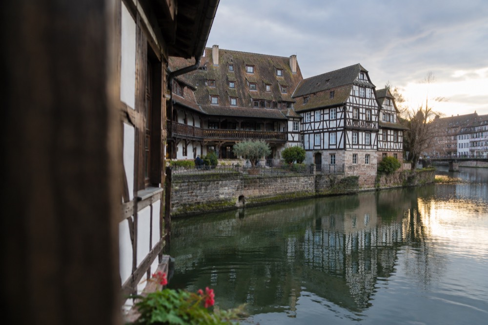 Riverside half-timbered houses reflected in the Ill at golden hour