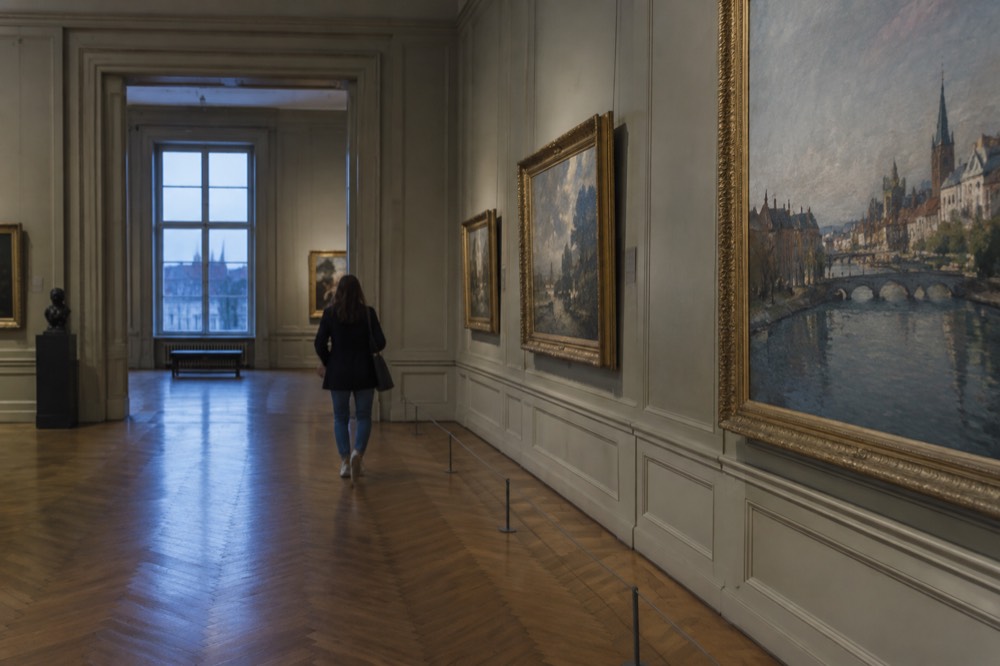 A museum gallery with paintings hung on panelled walls inside Palais Rohan