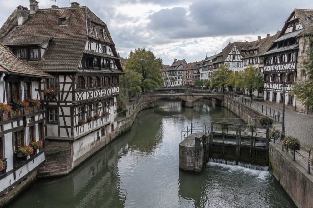 Half-timbered houses along a canal in Petite France, Strasbourg, with the river flowing beneath stone bridges