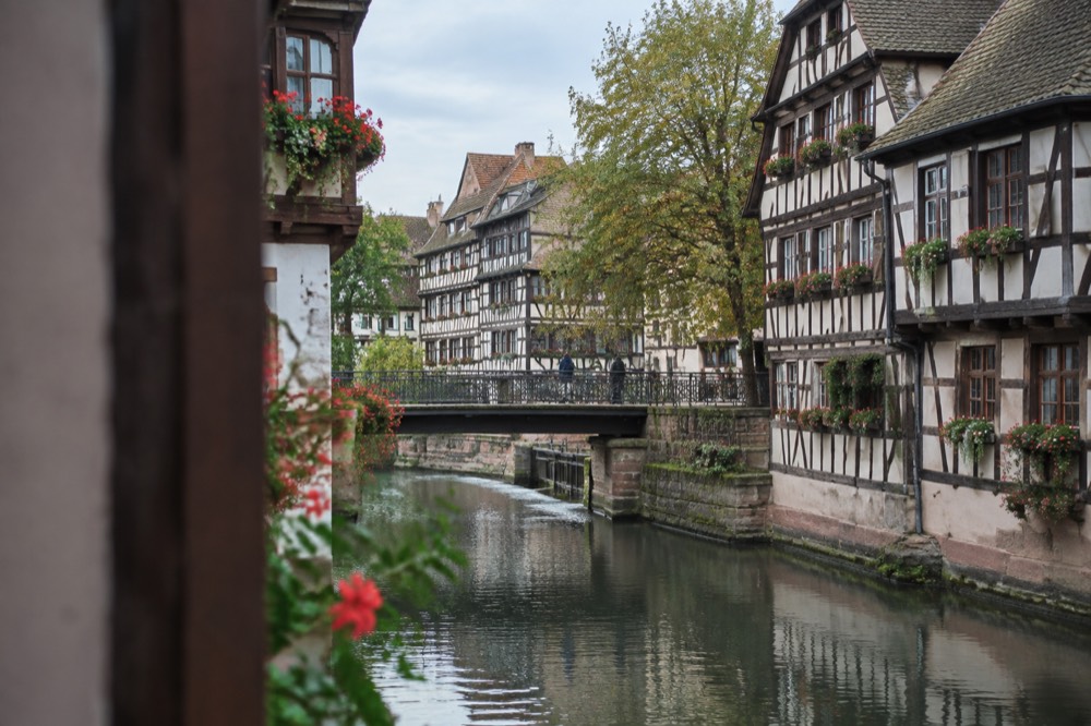 A footbridge over a calm canal in Petite France, Strasbourg, framed by timber-framed façades