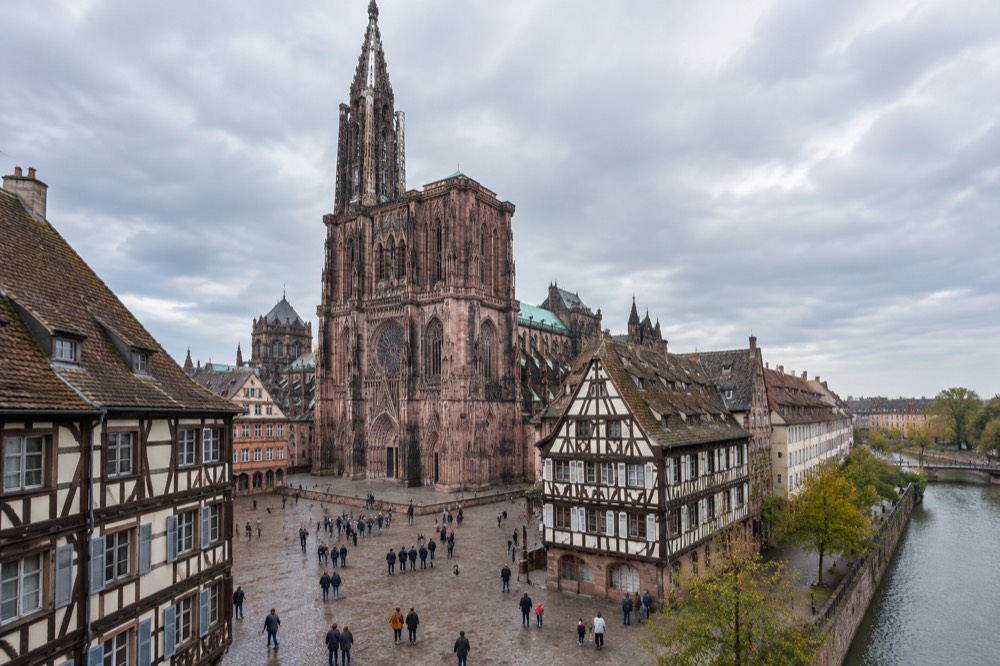 Families and visitors walking across an open paved square in Strasbourg old town