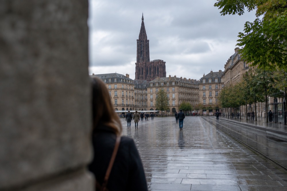 A view from Place Kleber towards the cathedral spire, with the square's stone paving and the statue of Kleber in the foreground
