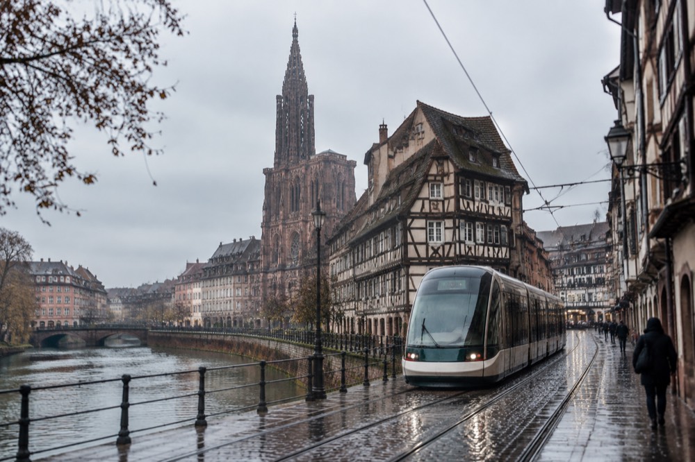 Tram passing through a Strasbourg street near the river with old buildings on both sides