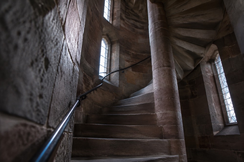 Stone spiral staircase inside a cathedral tower lit by small windows