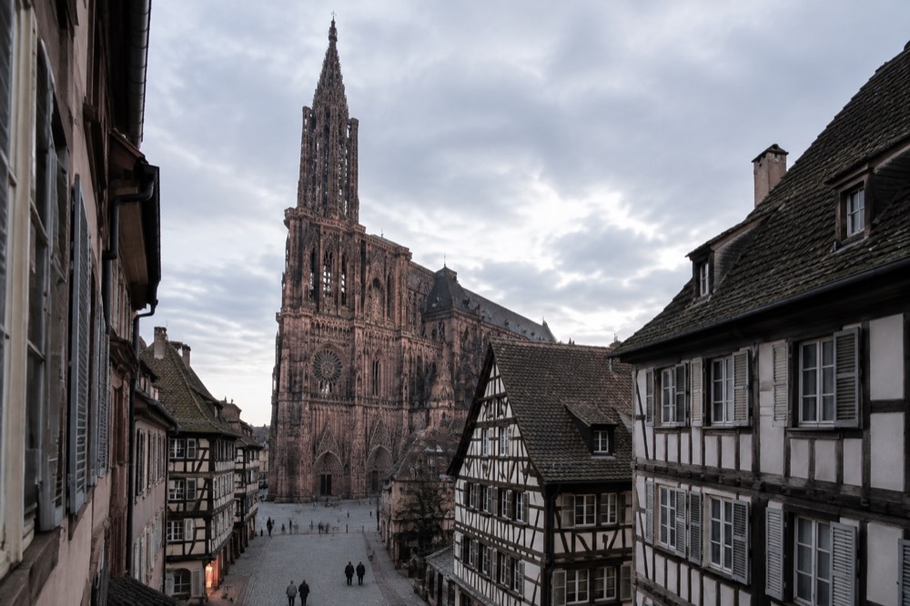 Half-timbered houses and a gothic church tower seen from a narrow old-town street