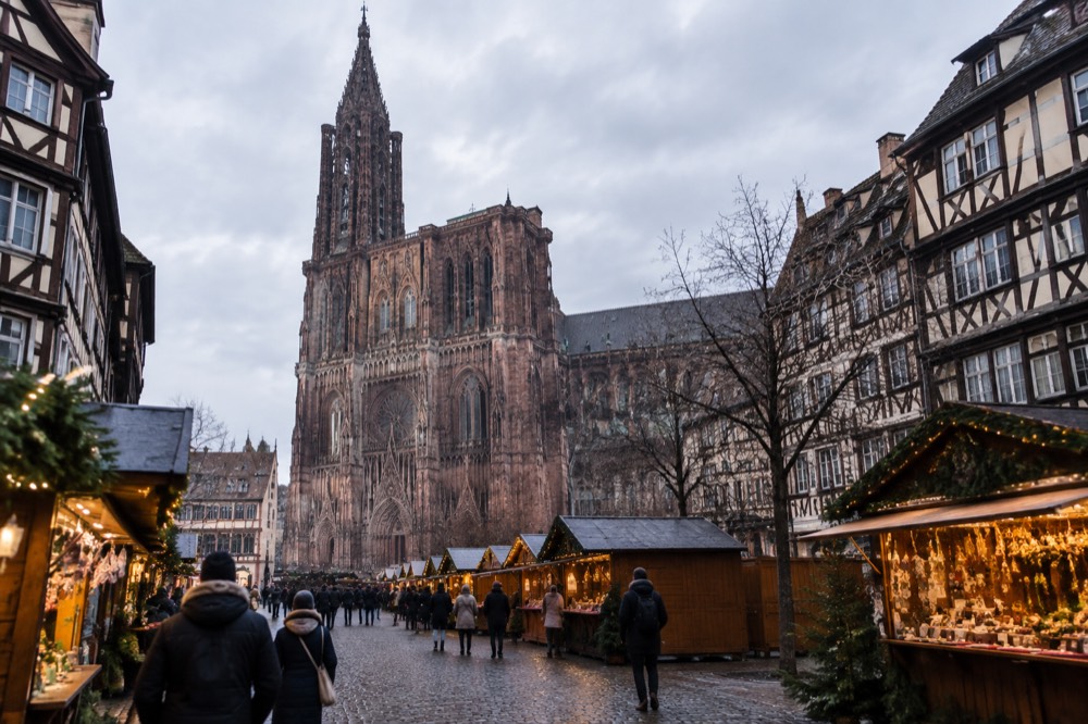 Festive market chalets and a gothic cathedral facade lit at dusk in winter