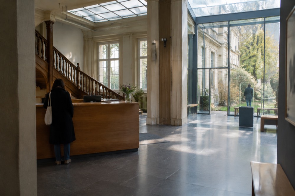 Museum entrance hall with a wooden counter and staircase under a glass light