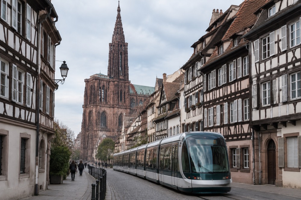 Modern Strasbourg tram passing timber-framed buildings on a city street