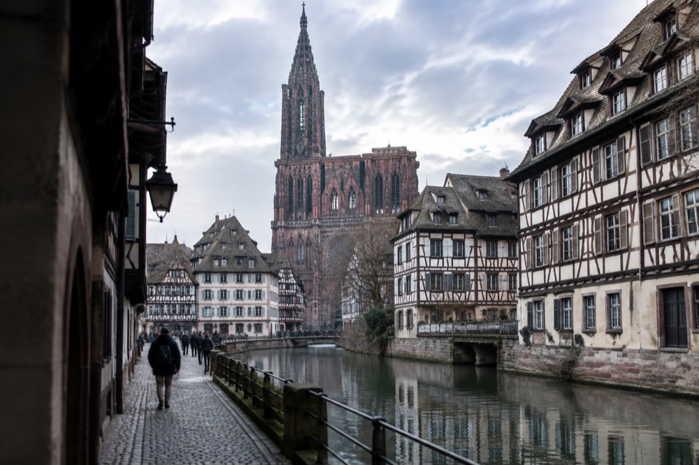 Half-timbered houses reflected in a canal along a Strasbourg riverside street