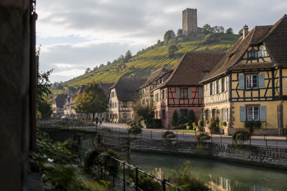 Stone rampart tower above rooftops and vineyards in an Alsatian wine village