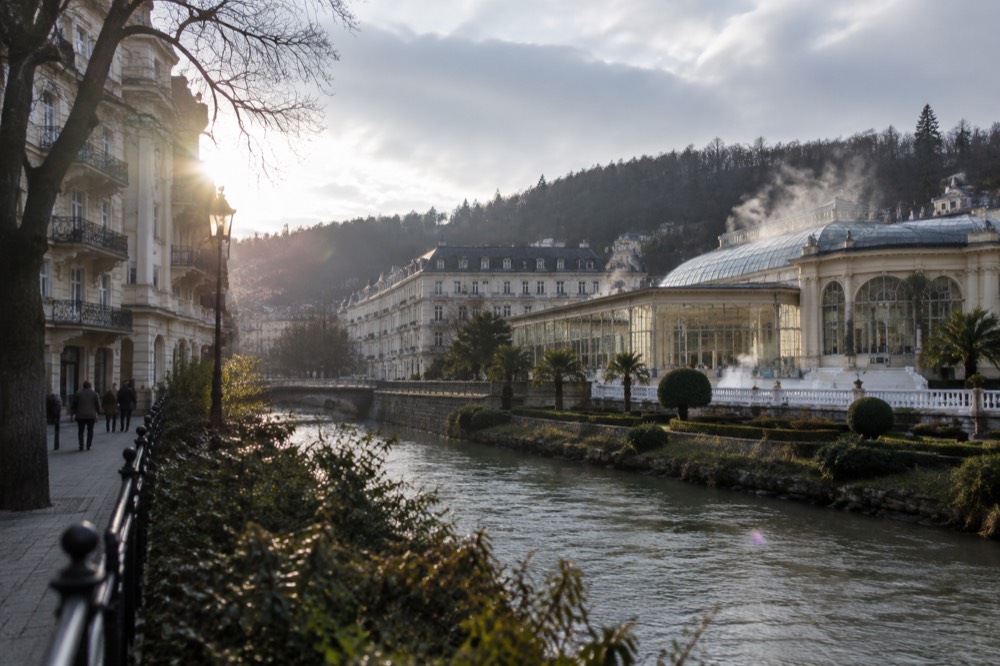 Thermal bath building with glass walls and steaming water beneath a glass roof