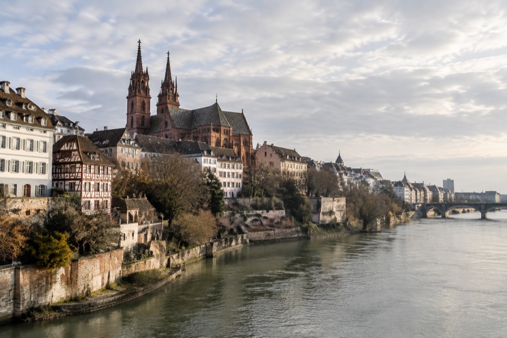 The Rhine river flowing past Basel old town with the Minster towers rising above riverside buildings