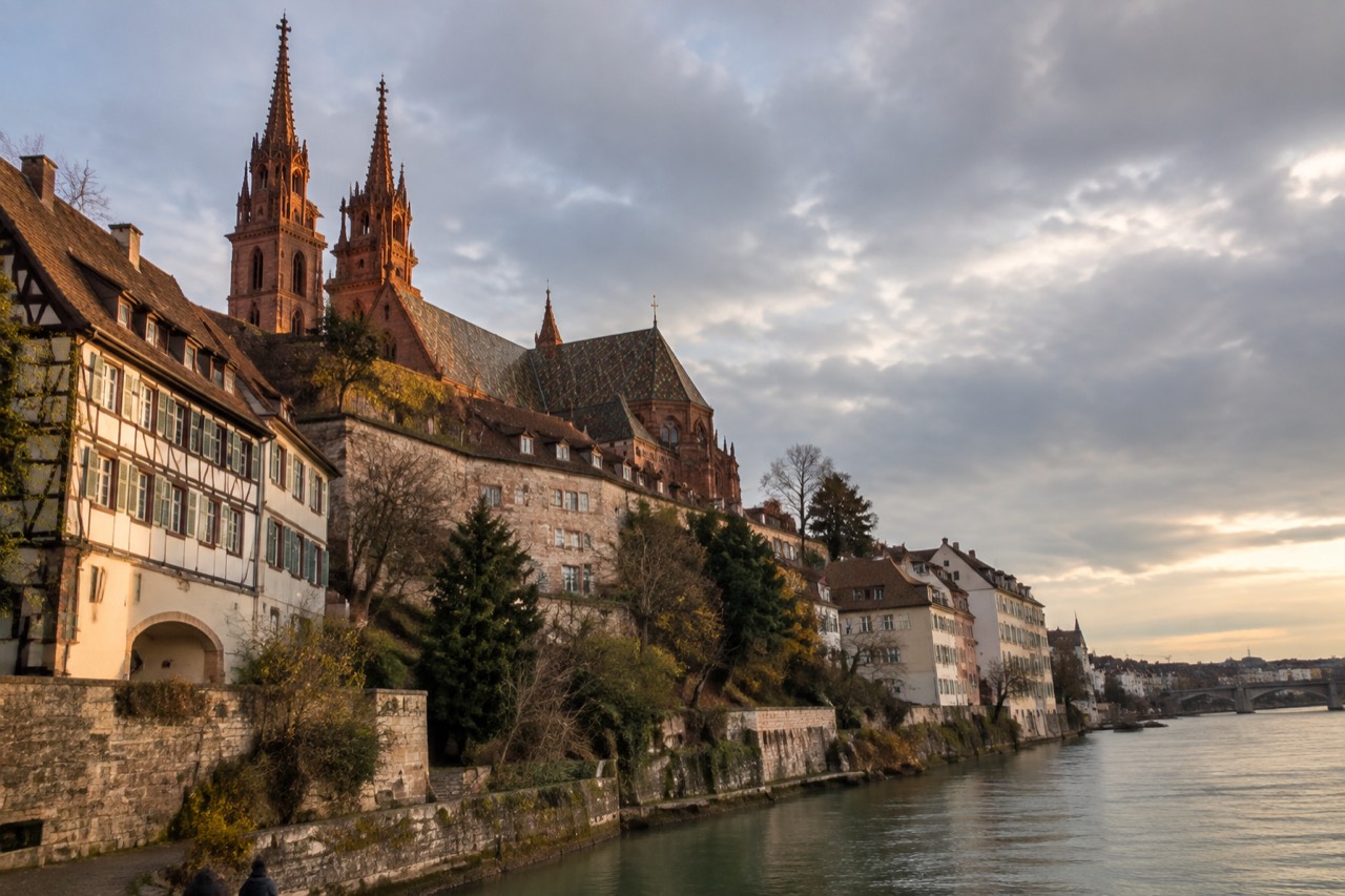 The Rhine river flowing past Basel old town with the Minster towers rising above riverside buildings