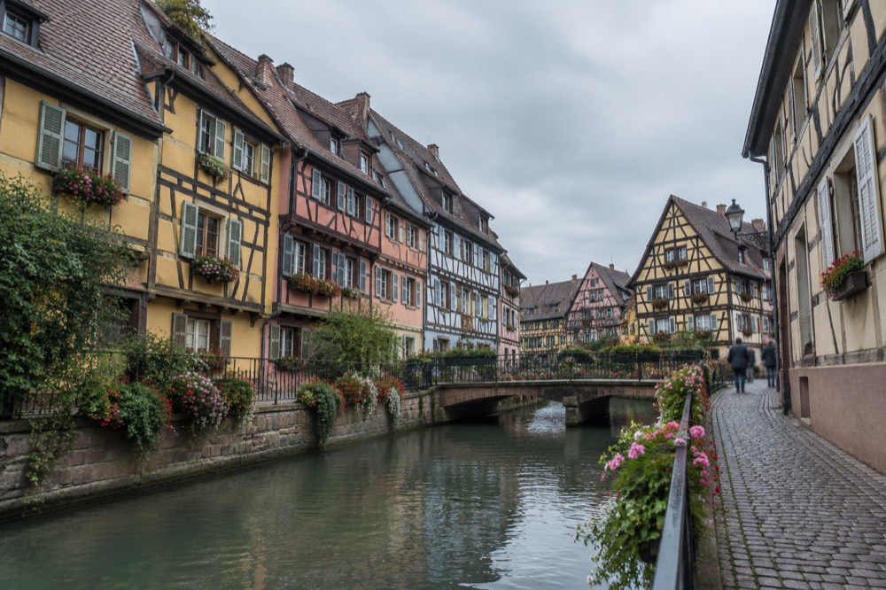 Narrow cobbled street in Colmar lined with half-timbered houses and shop signs