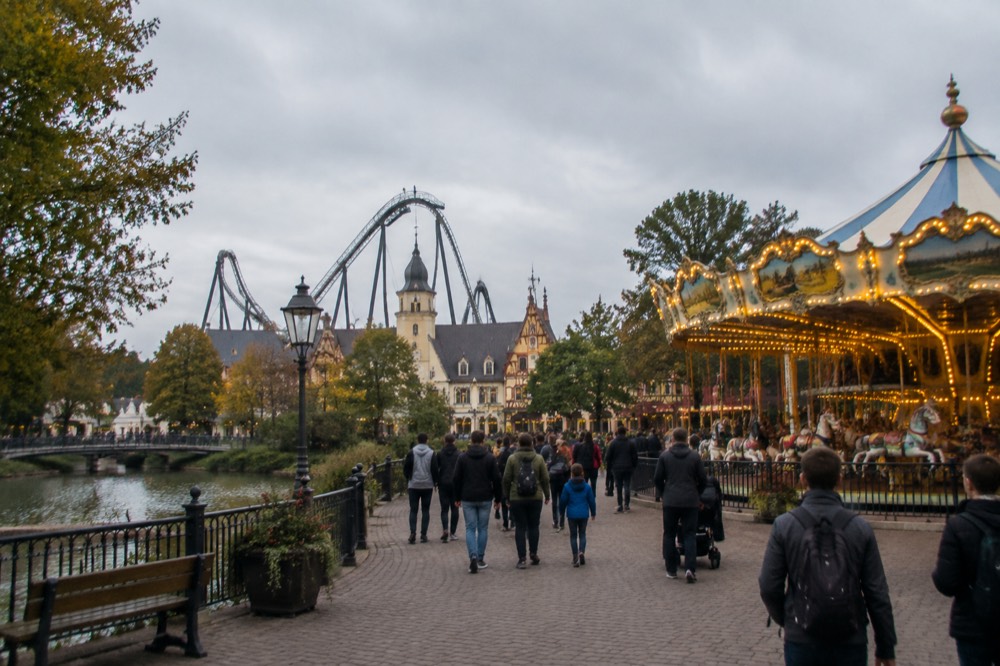 Evening light over a theme park plaza with a carousel and illuminated facades