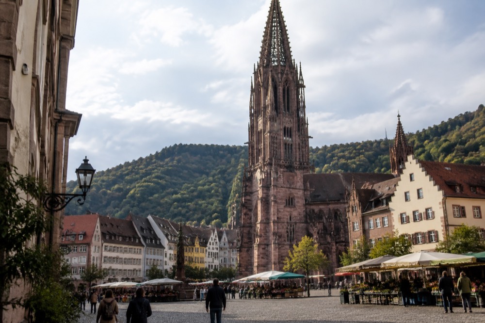 Red sandstone minster tower above a German old town with market square and gabled rooftops