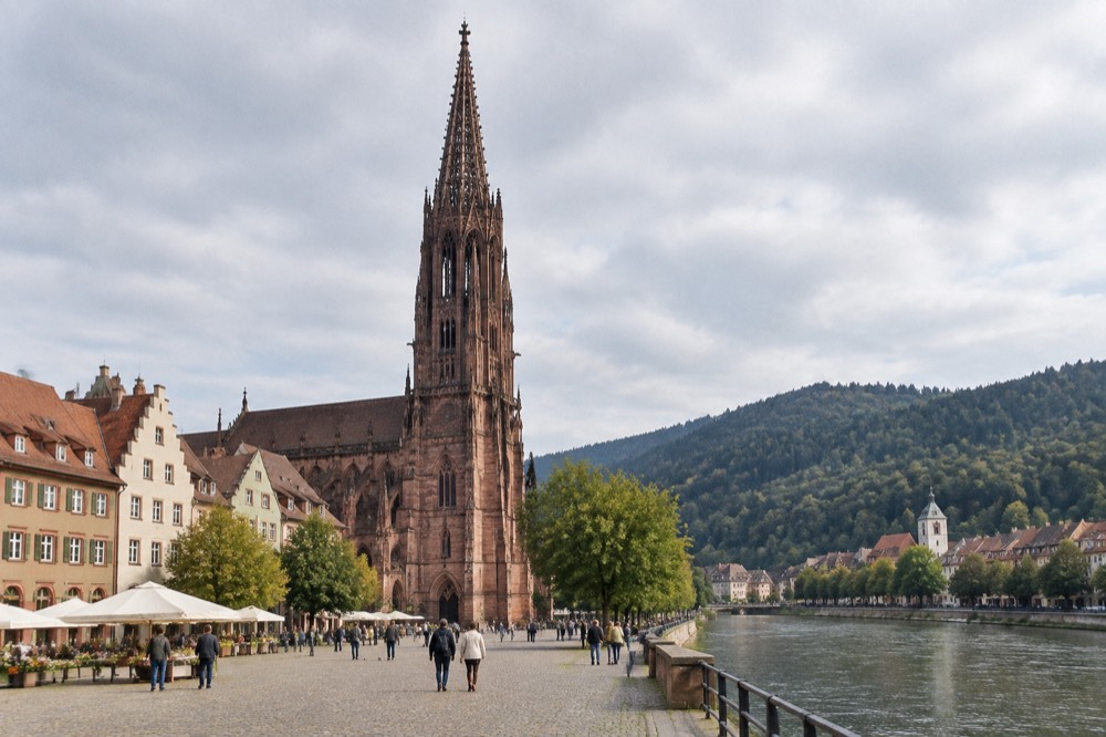 Dark forested hills above a still mountain lake with a small promenade town on the shore