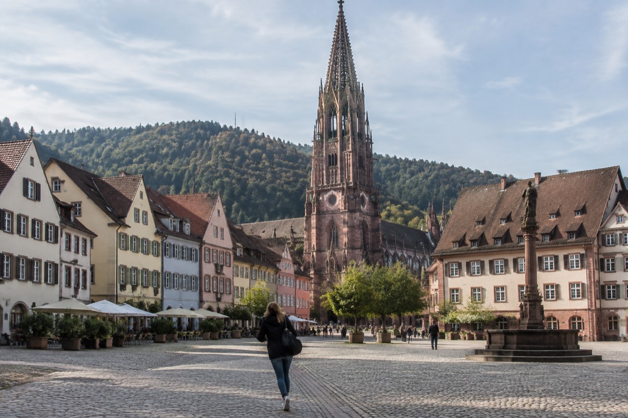 Red sandstone minster tower above a German old town with market square and gabled rooftops