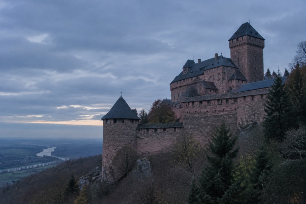 A stone watchtower and ramparts seen from below against a cloudy sky