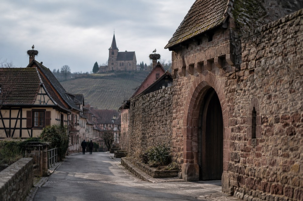 A stone rampart wall with a fortified gate beside a village street