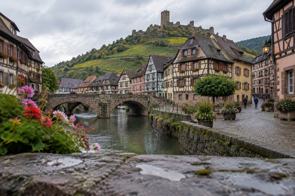 A quiet cobbled village square with painted timber façades in soft evening light