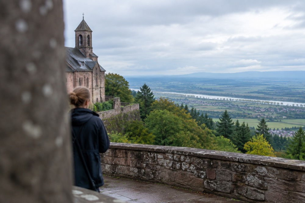 A stone parapet terrace overlooking the wide green plain of Alsace with distant hills on the horizon