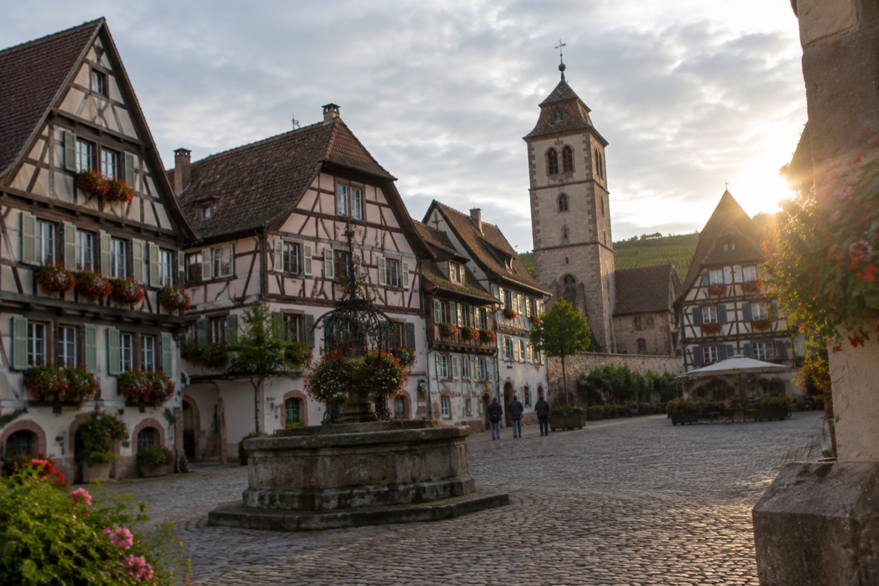 Half-timbered houses with flower boxes around a small square in a walled Alsatian wine town