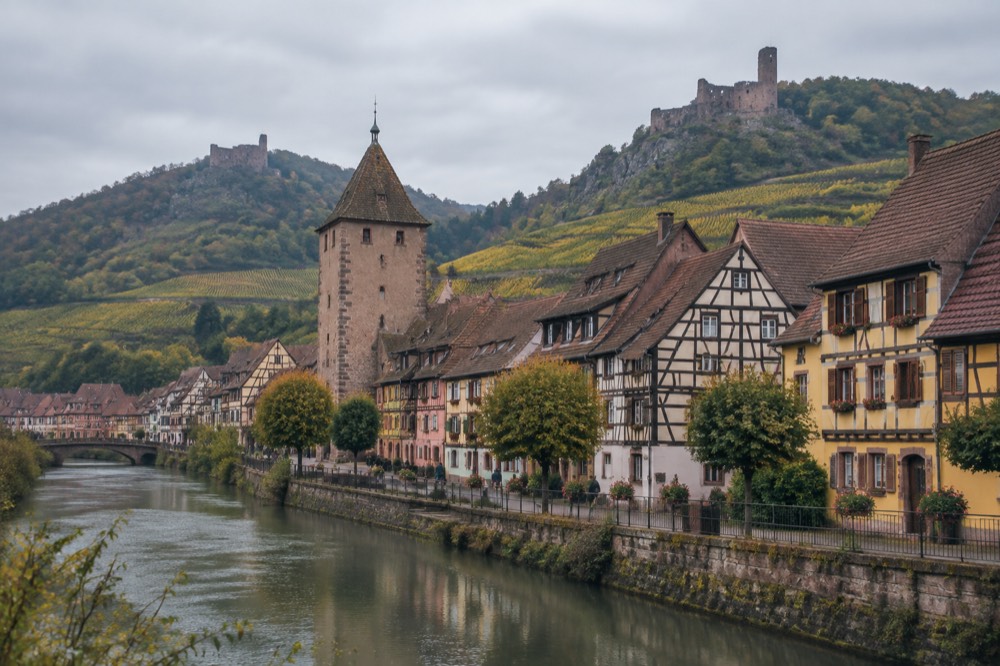 Half-timbered wine village houses beneath vineyard slopes in Alsace
