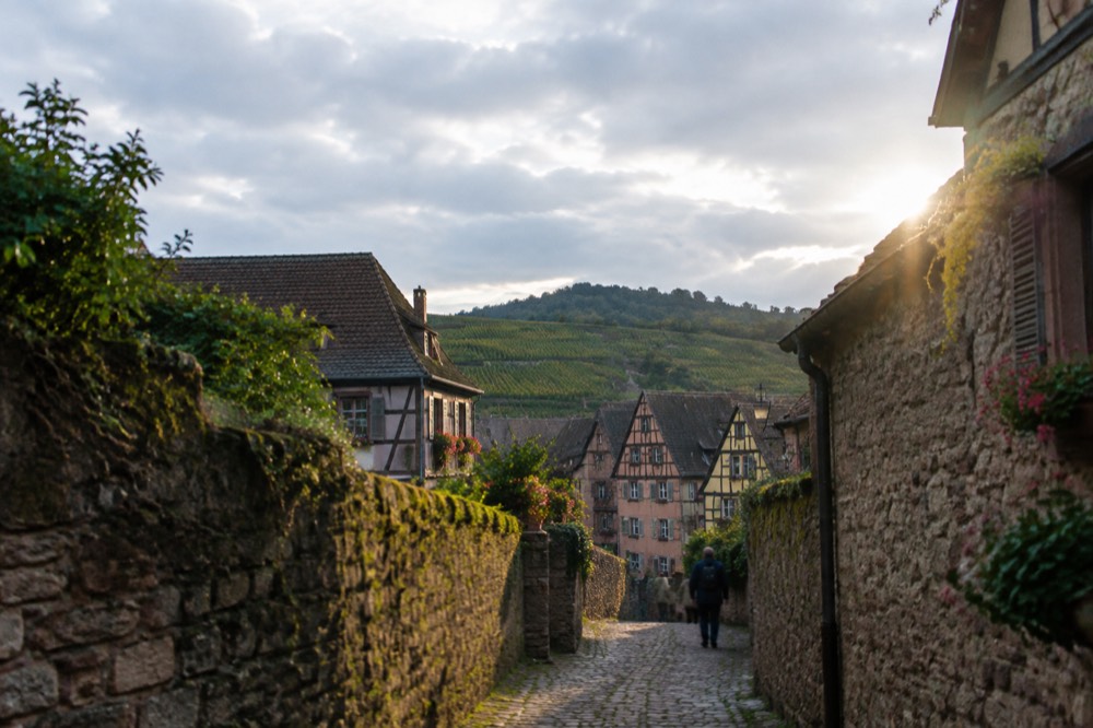 A narrow lane between old stone walls inside a wined village in Alsace