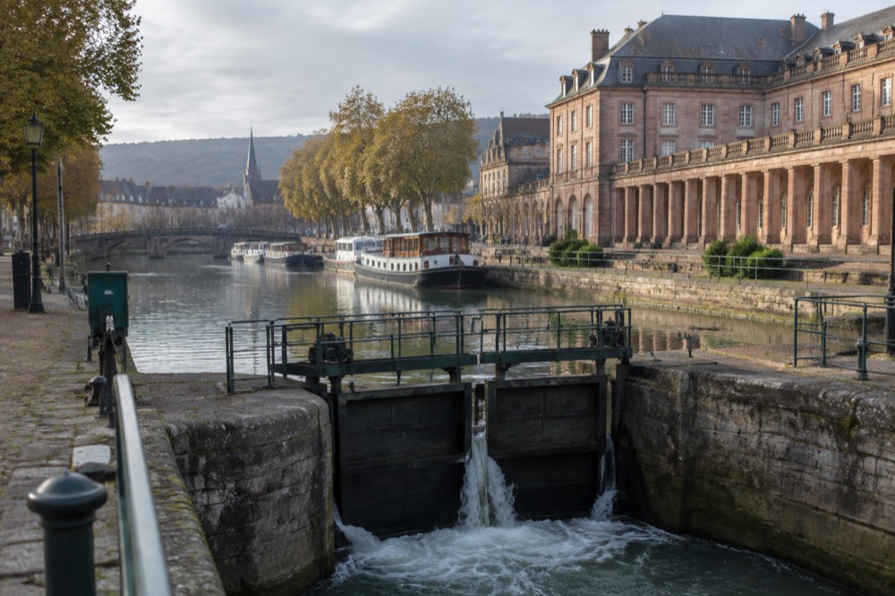 A canal lock gate with water flowing through in a small French town