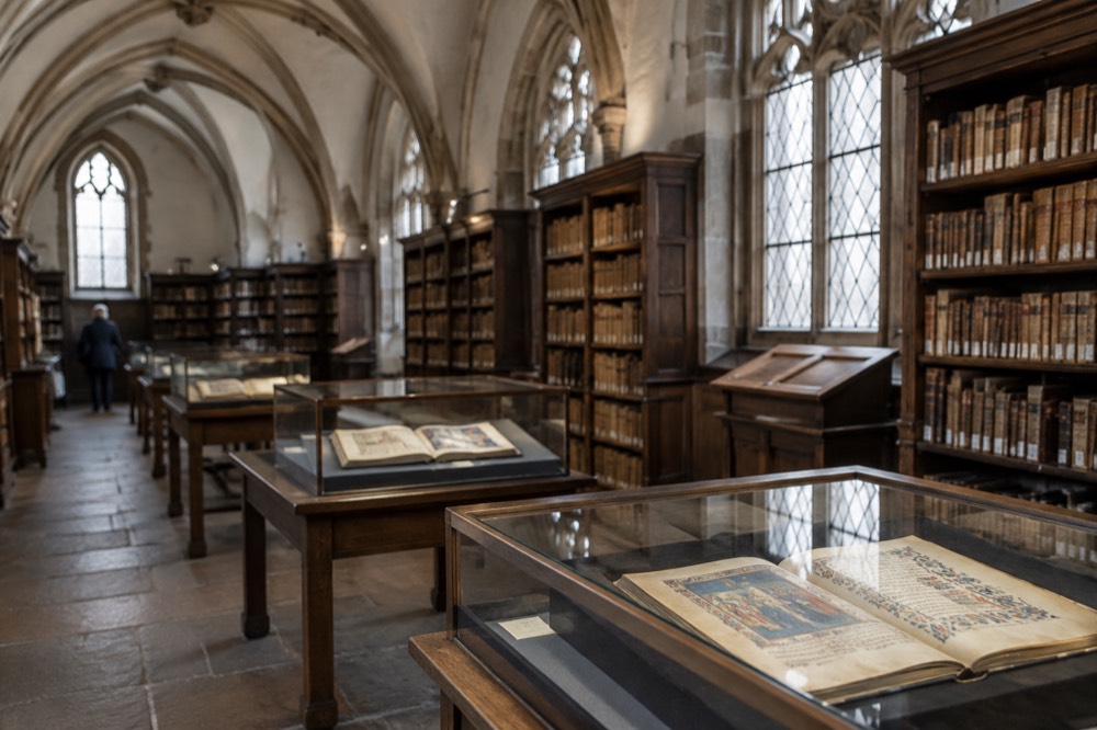 The reading room of the Humanist Library in Sélestat, with dark wooden shelves, illuminated manuscripts in display cases and a vaulted ceiling