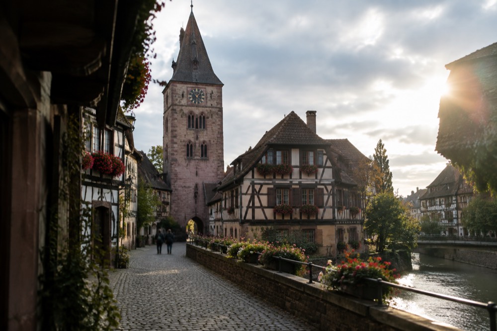 The Tour de l'Horloge, a medieval gate tower in Sélestat, with its clock face and pointed roof, framed by half-timbered houses and a cobbled street