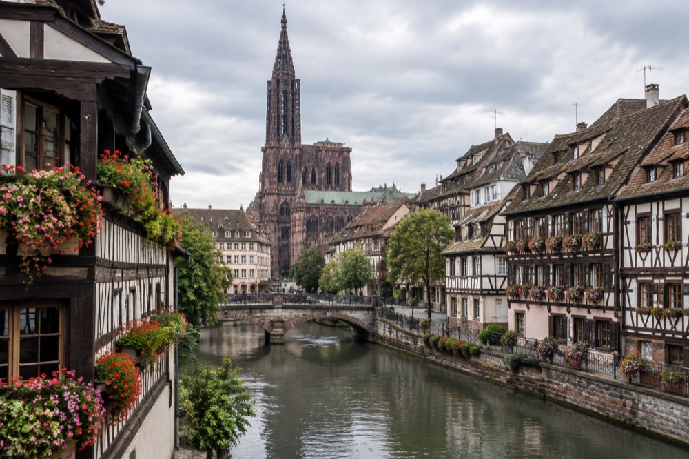Half-timbered houses along a canal in Strasbourg, France, with flowers on the balconies