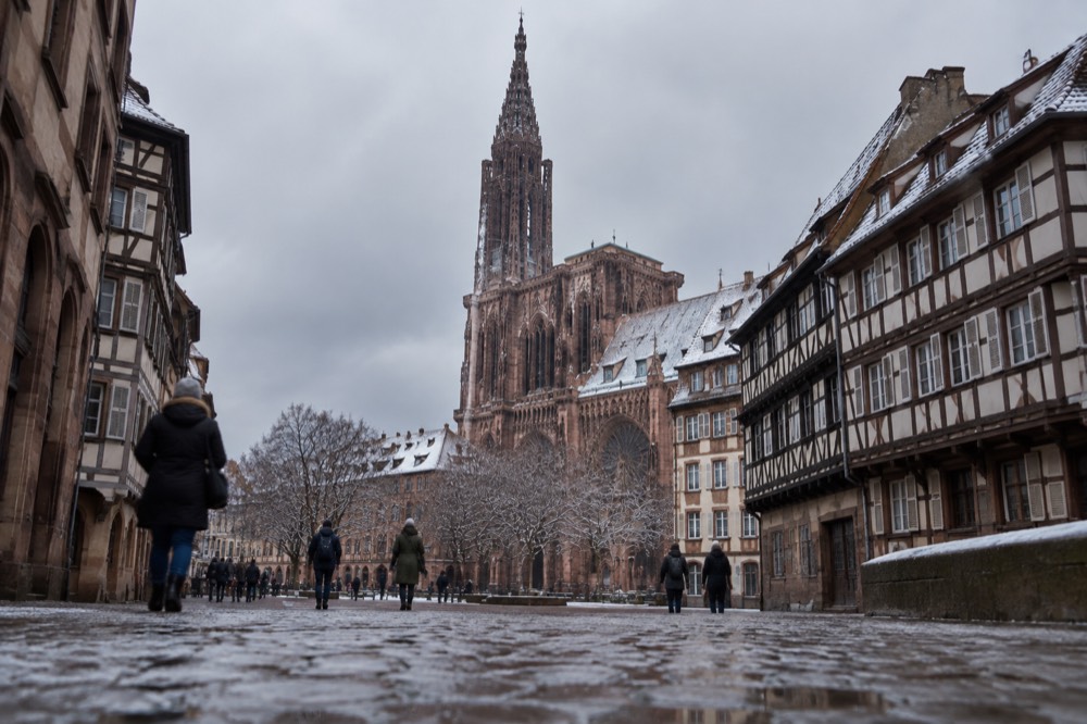The single spire of Strasbourg Cathedral rising above snow-dusted rooftops