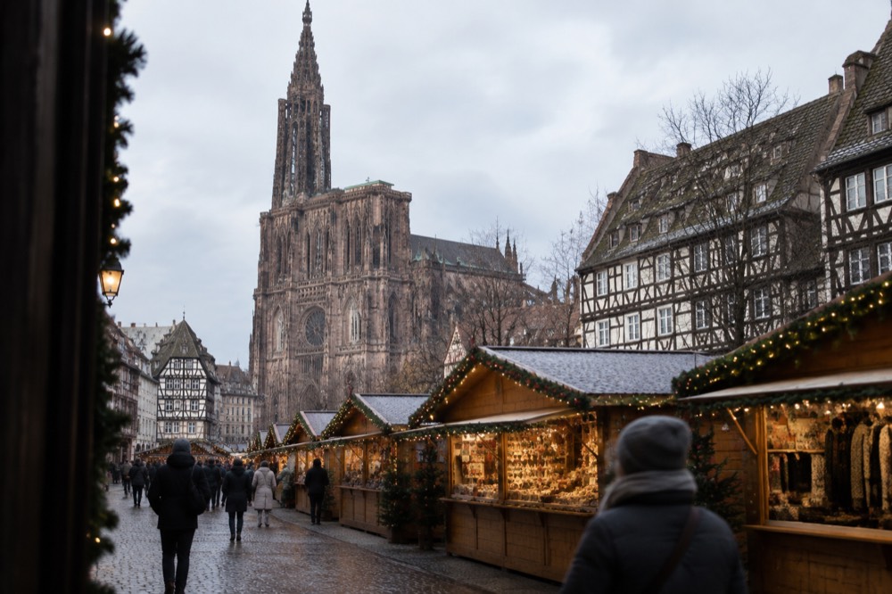 A row of wooden Christmas market chalets with garlands and evening lights in Strasbourg