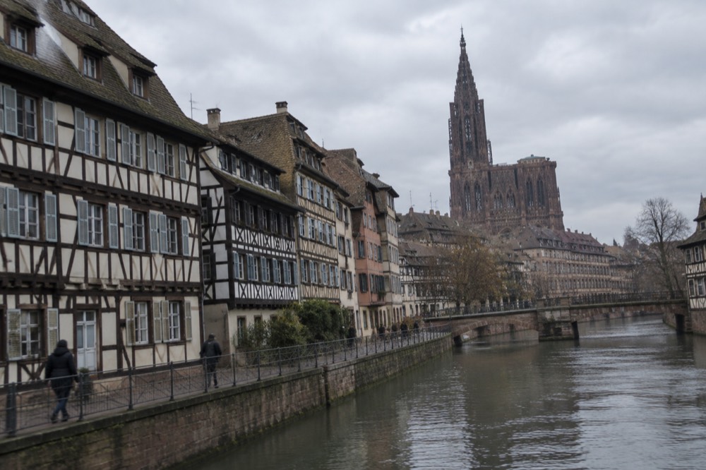 Half-timbered houses along the Ill river in Strasbourg with the cathedral spire in the distance