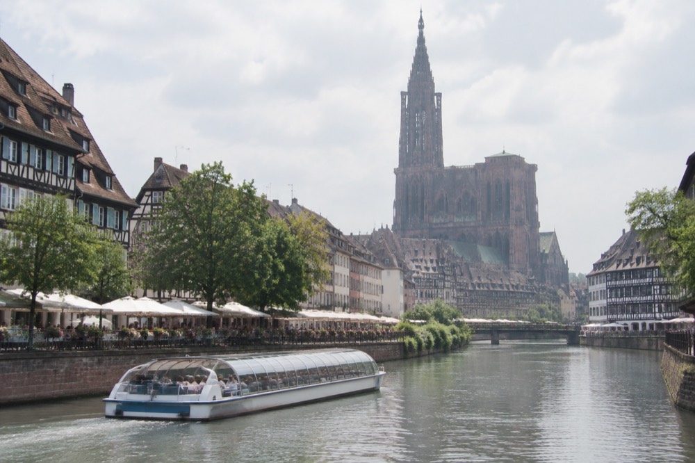 A sightseeing boat cruising the Ill river past summer terraces in Strasbourg