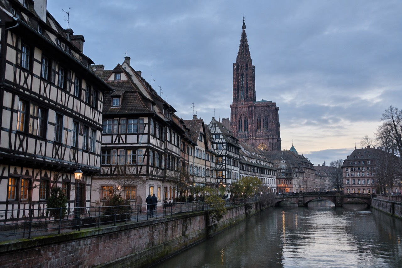 Half-timbered houses along the Ill river in Strasbourg with the cathedral spire in the distance