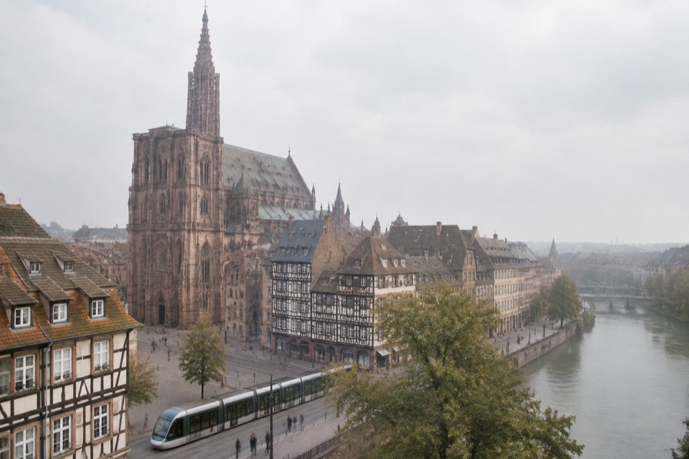A modern tram passing in front of half-timbered buildings on a Strasbourg street
