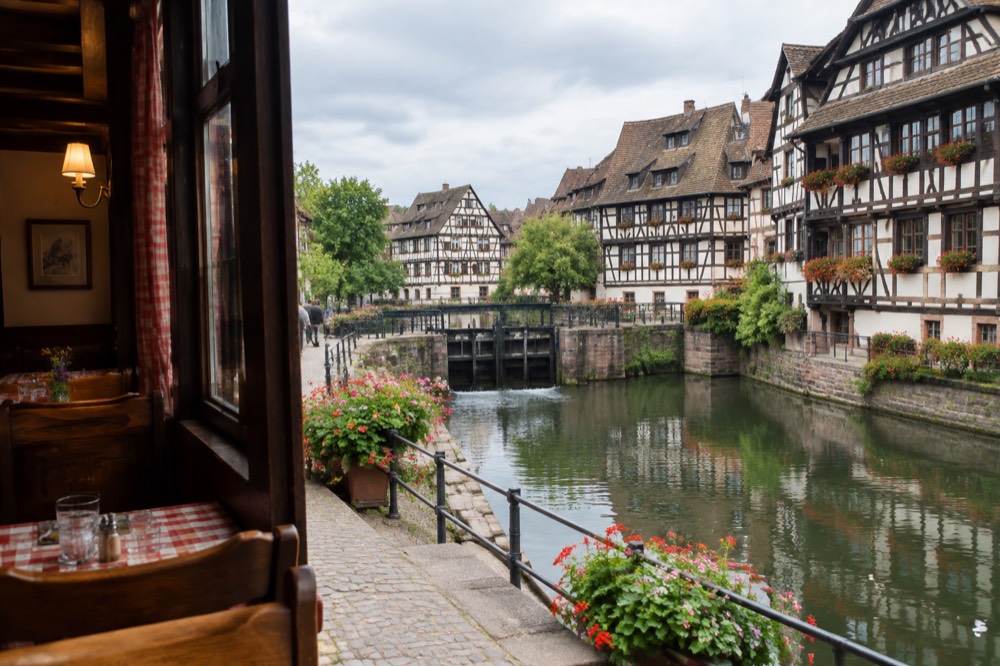 A cosy winstub interior with wooden benches, checked tablecloths and a chalkboard menu in Strasbourg old town