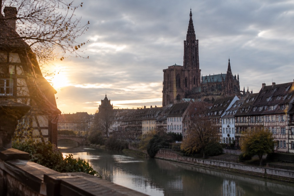 Strasbourg Cathedral and old town rooftops seen at dusk from a terrace above the Ill river
