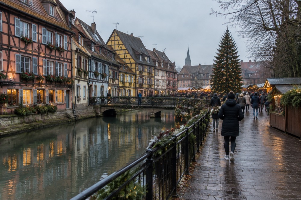 A decorated Christmas tree above a market square with evening crowds