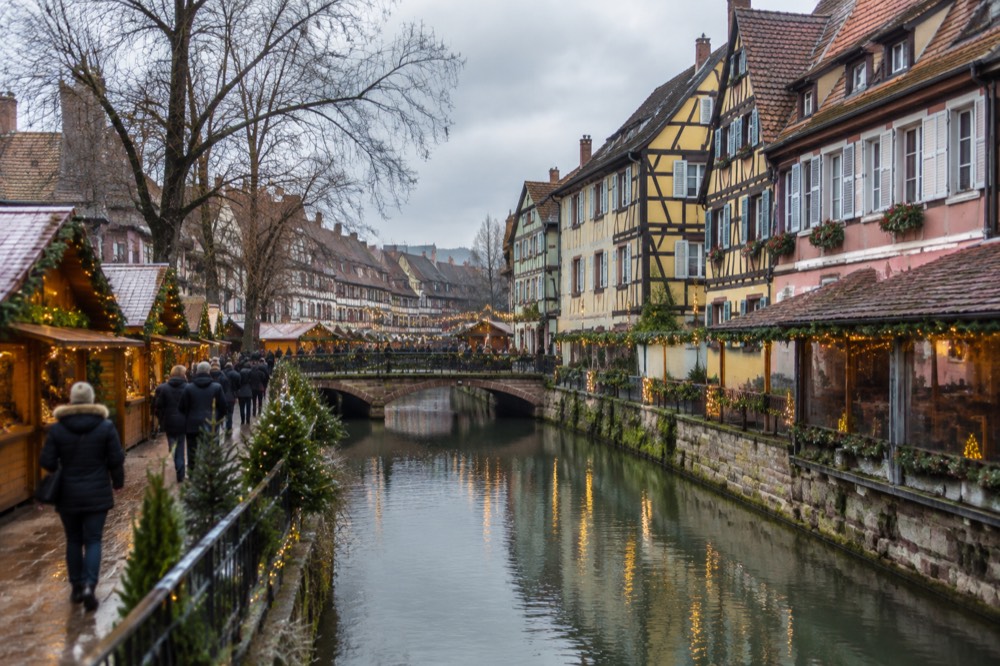 Festive chalets and warm string lights along a canal in Colmar's old town