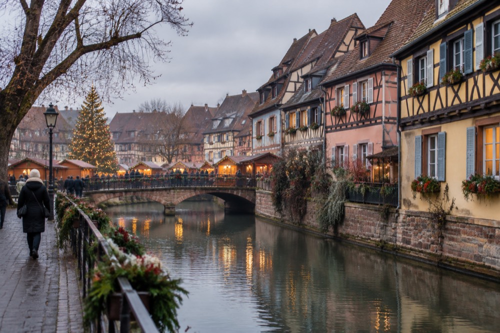 A Christmas market square with an illuminated tree and stalls at dusk