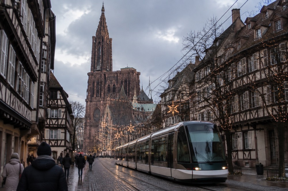 A tram passing festive lights on a Strasbourg street in December
